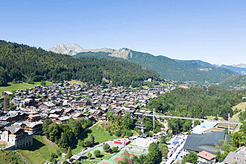A wooden table and chairs on a balcony overlooking a mountain range