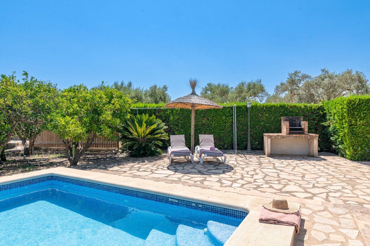 A swimming pool with chairs and an umbrella in the background