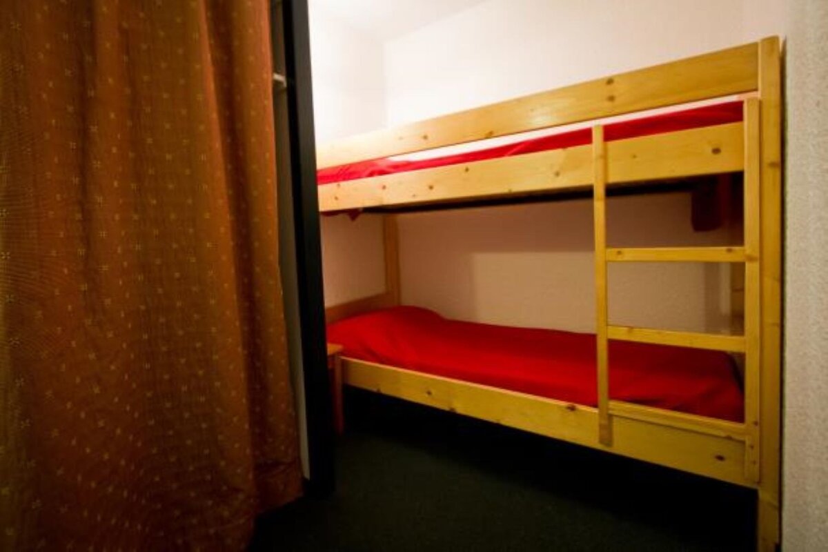 A bunk bed with red sheets and a ladder
