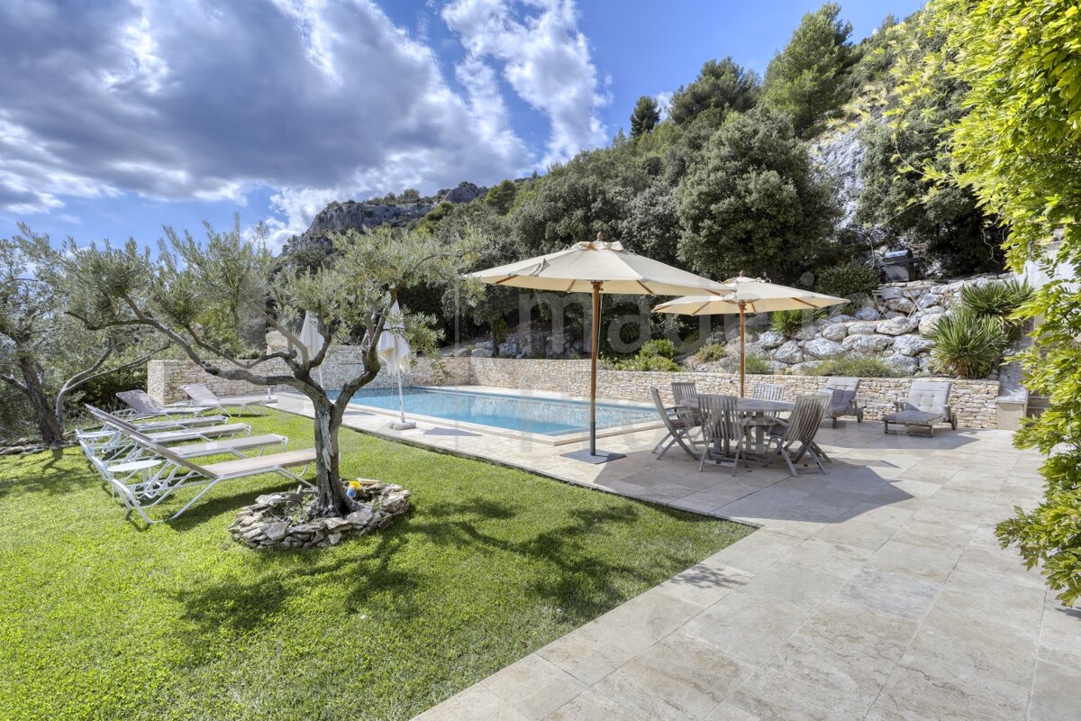 A patio with umbrellas and chairs in front of a swimming pool