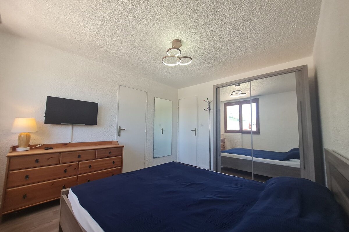 A bedroom with a bed a dresser and a flat screen tv