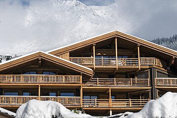 A large wooden house with a mountain in the background