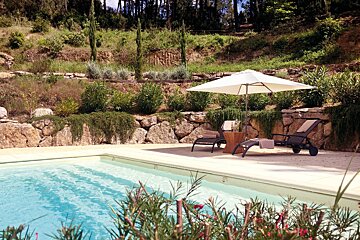 A white umbrella sits on the edge of a swimming pool