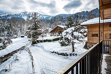 A balcony overlooking a snowy landscape with mountains in the background