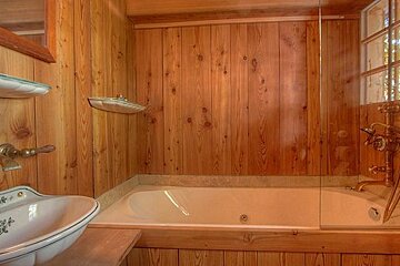 A bathroom with a sink , tub , shower and wooden walls