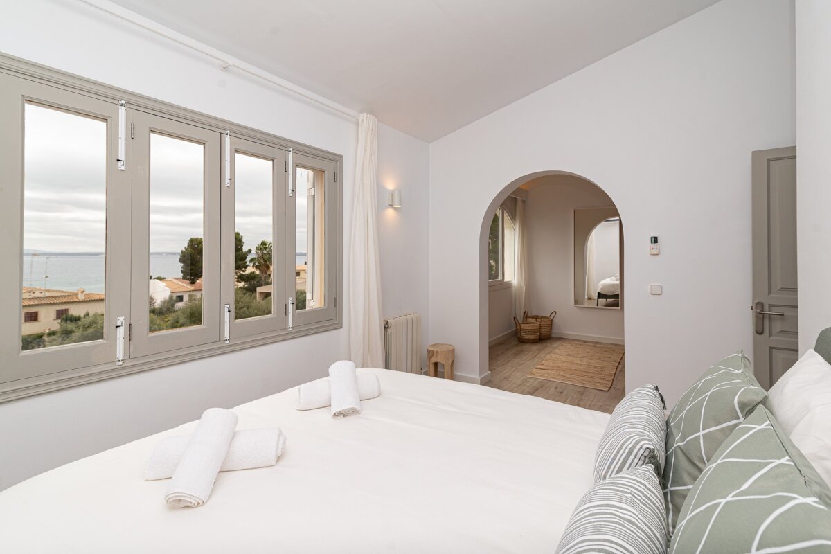 A bedroom with a bed and a window with a view of the ocean