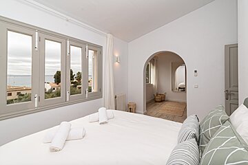 A bedroom with a bed and a window with a view of the ocean