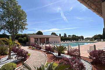 A swimming pool surrounded by chairs and bushes on a sunny day