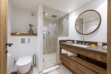 A bathroom with a toilet a sink and a round mirror