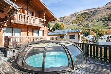 A wooden house with a swimming pool in front of it