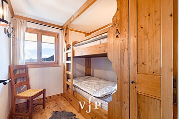 A bedroom with a bunk bed and a chair and the letter vjp on the door