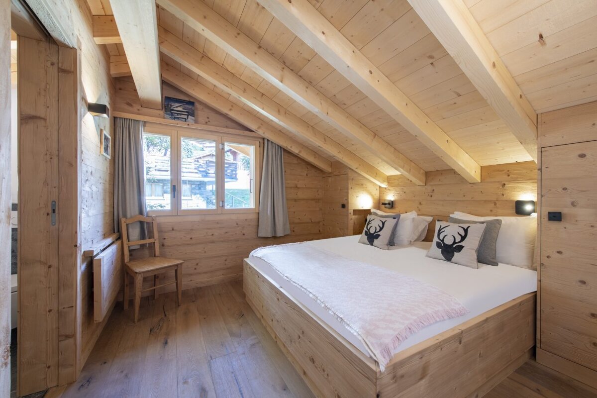 A bedroom with a wooden bed and a chair