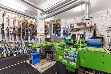 A green machine in a room with skis hanging on the wall