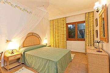 A bedroom with a canopy bed and yellow curtains