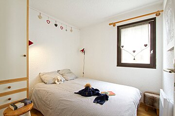 A bedroom with a bed and hearts hanging from the ceiling