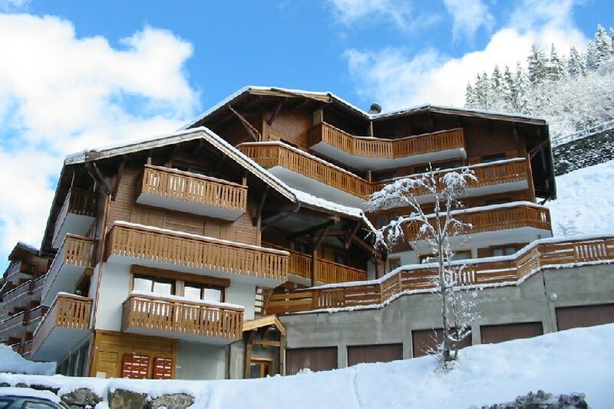 A large building with a lot of windows sits on top of a mountain