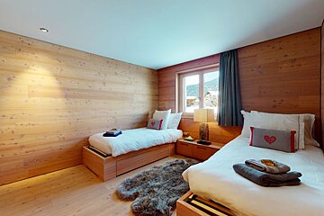 A bedroom with two beds and a rug on the floor