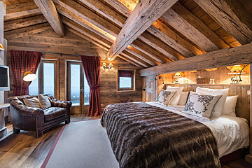 A bedroom with a large bed and a chair