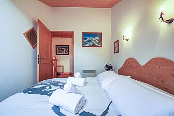 A bedroom with a painting on the wall above the bed