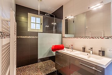 A bathroom with two sinks and a walk in shower