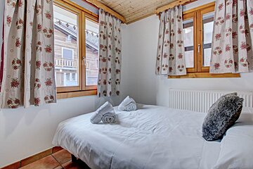 A bedroom with a bed and a window with floral curtains