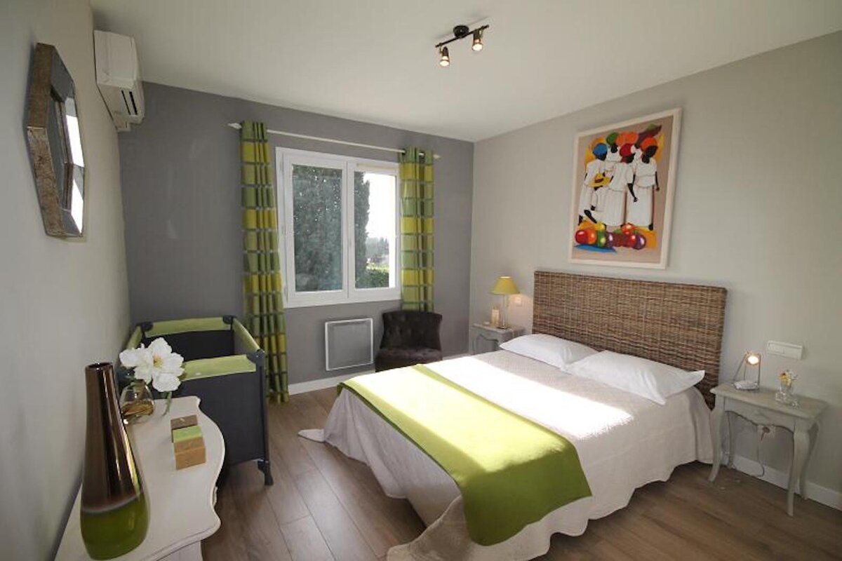 A bedroom with a bed a crib and a painting on the wall