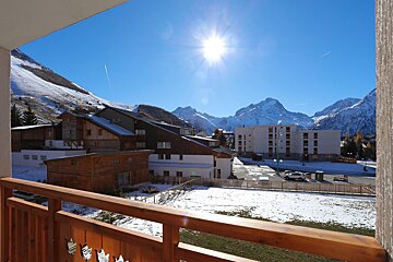 A balcony with a view of snowy mountains and buildings