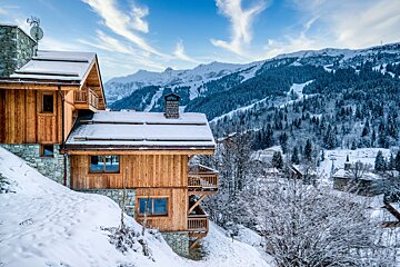A snowy mountain landscape with a house in the foreground