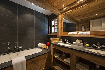 A bathroom with two sinks and a bathtub with a candle on the counter