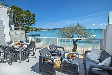 A balcony with a table and chairs overlooking the ocean