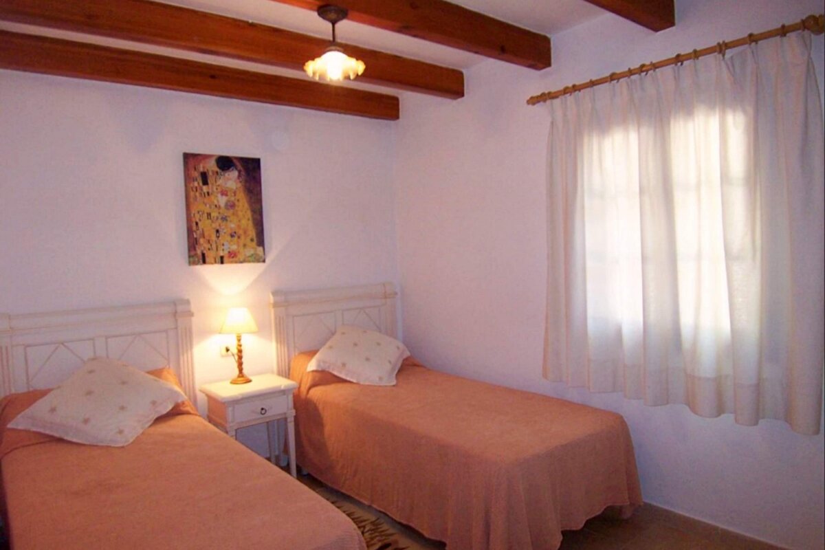 A bedroom with two beds and a painting on the wall