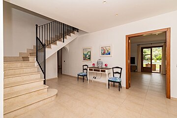 A hallway with stairs and a table with vases on it
