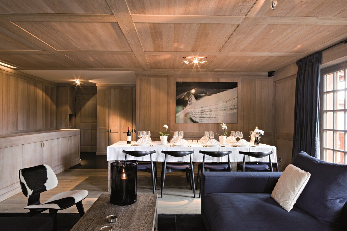 A dining room with a table and chairs and a painting on the wall