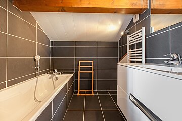 A bathroom with a bathtub a sink and a towel rack