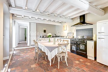 A white refrigerator sits in a kitchen with a table and chairs