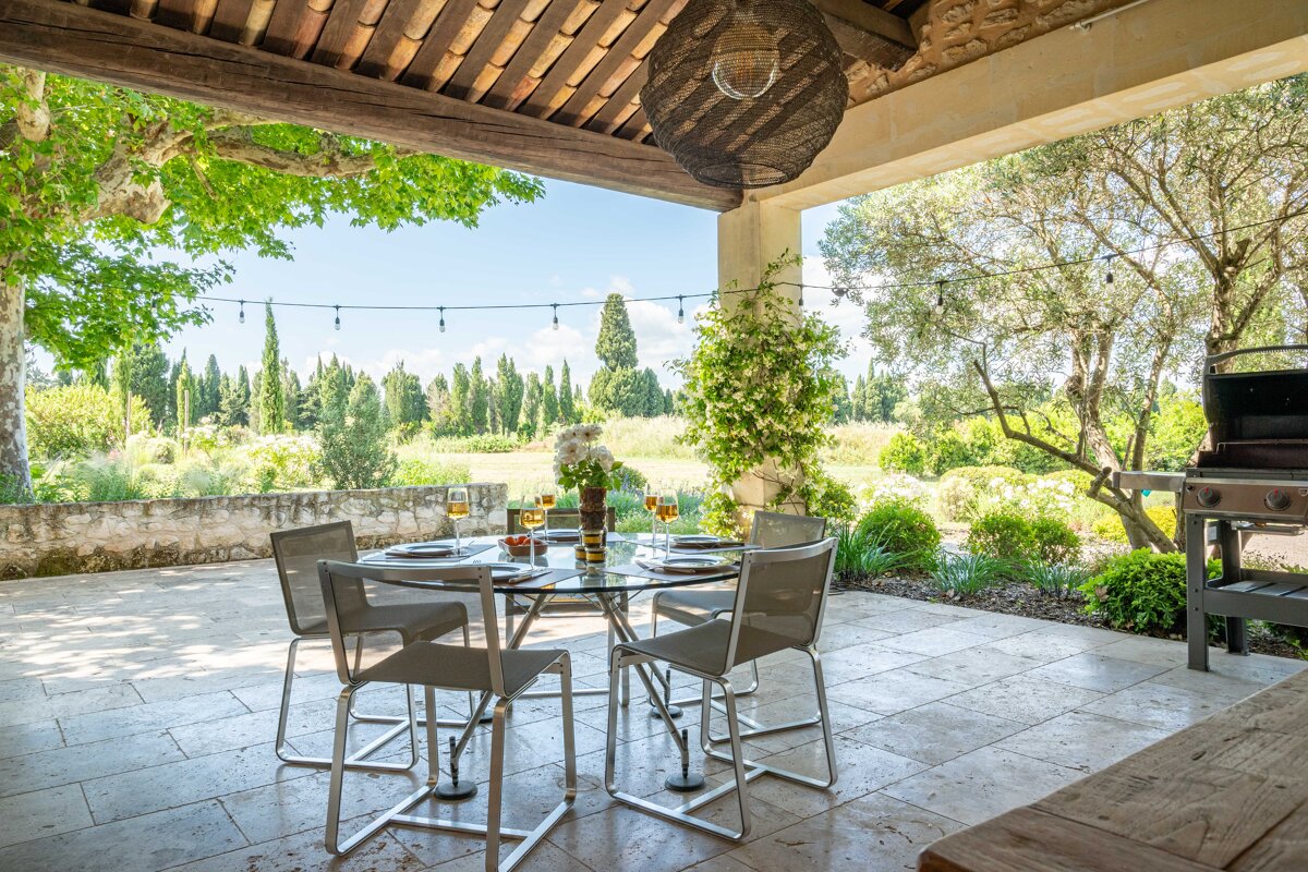 A patio with a table and chairs and a grill