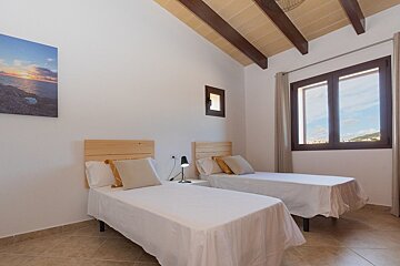 A bedroom with two beds and a painting on the wall