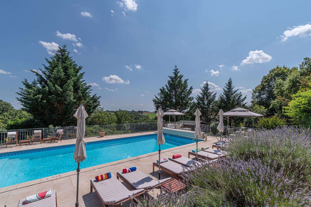 A large swimming pool with umbrellas and chairs around it