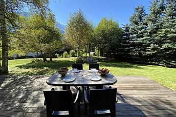A table with a bowl of fruit on it sits on a wooden deck