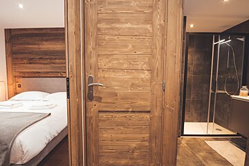 A bedroom with a wooden door leading to a bathroom