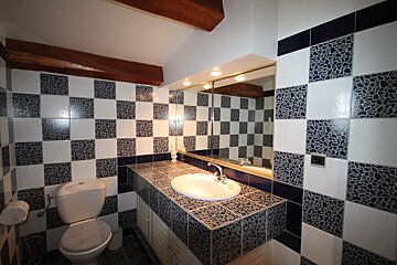 A bathroom with blue and white tiles and a toilet