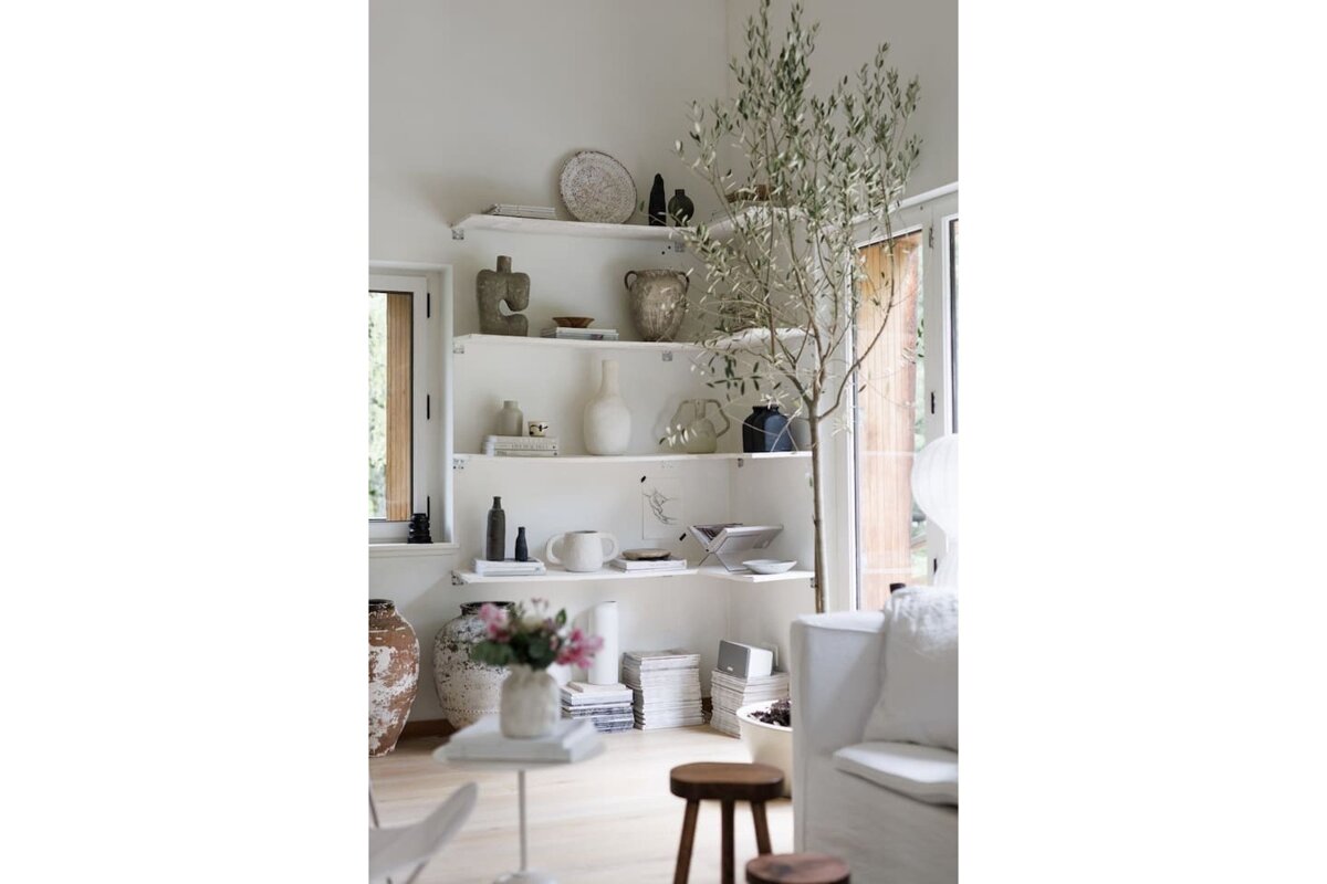 A living room with white shelves filled with vases and books