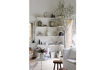 A living room with white shelves filled with vases and books