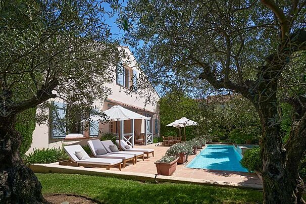 A white house with a swimming pool in front of it