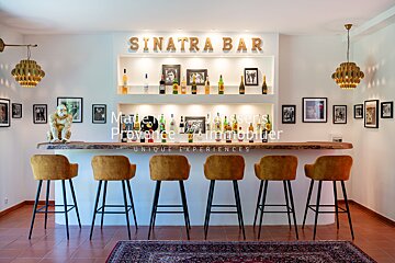 A bar with stools and a sign that says sinatra bar