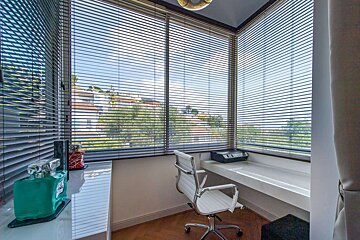 A white office chair sits in front of a window with blinds
