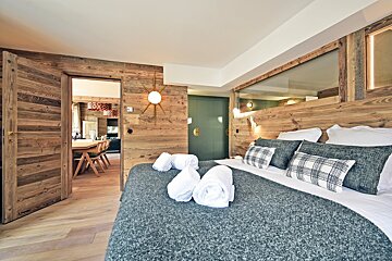 A bedroom with a large bed and a wooden wall