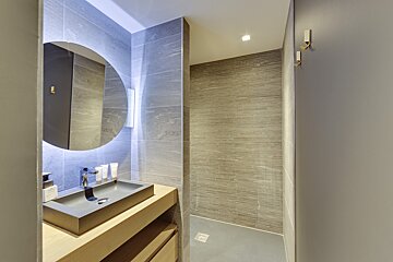 A bathroom with a round mirror and a sink