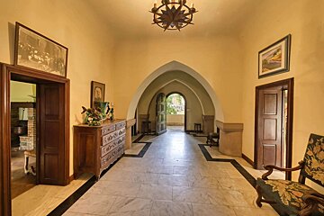 A hallway with a dresser and chairs in it