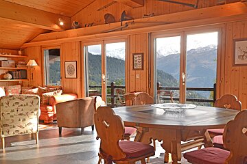 A living room with a table and chairs and a view of the mountains